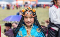 Ung kvinna i traditionella kläder under hästfestivalen väster om Litang